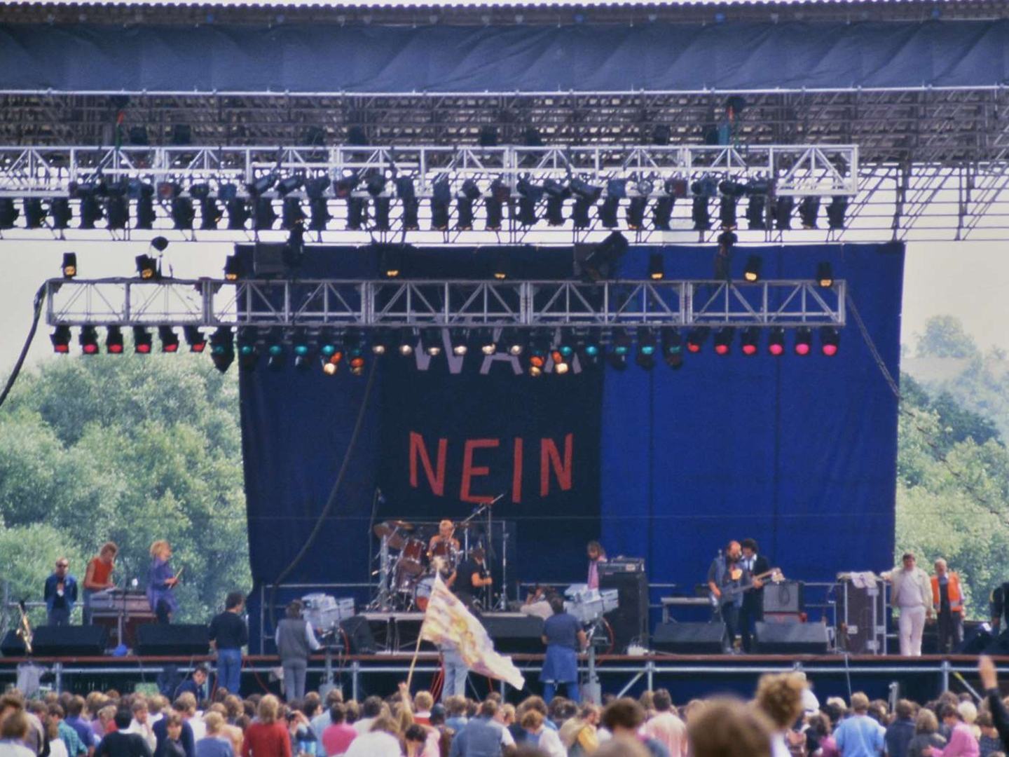 Eine große Festivalbühne mit dem Wort Nein vor einem dichten Publikum.