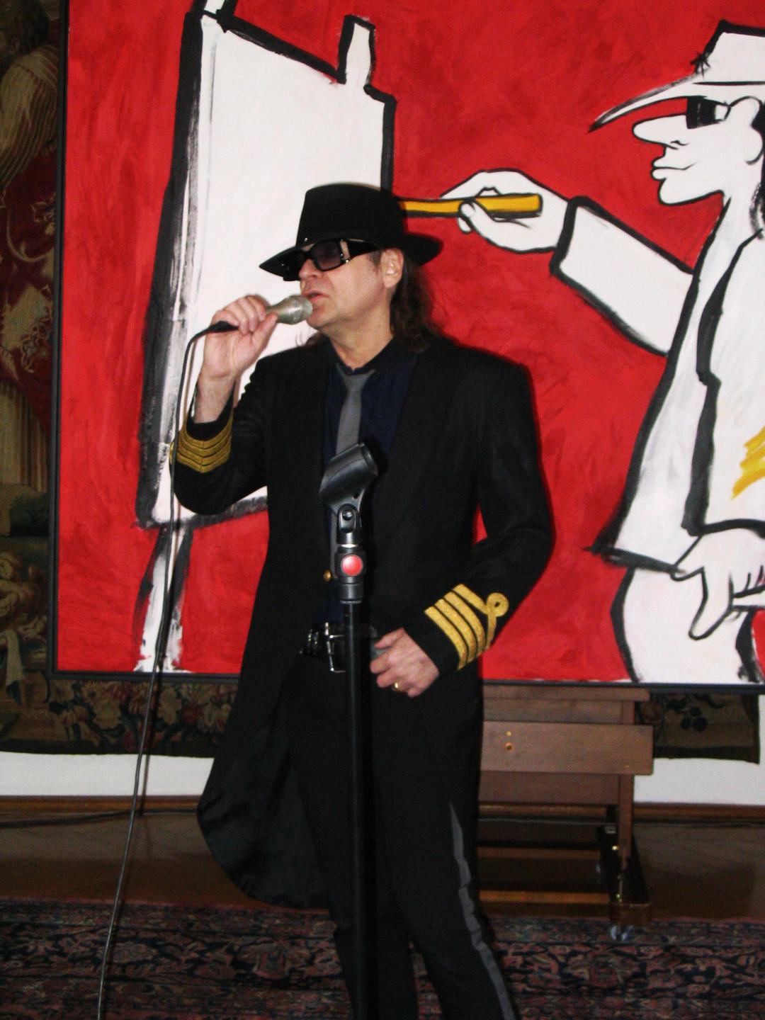 Udo Lindenberg spricht 2005 in Bonn vor rotem Hintergrund in ein Mikrofon.